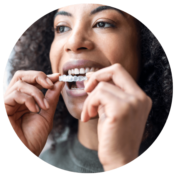 Woman placing invisalign on her top teeth